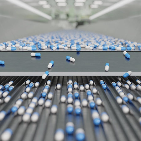line of white and blue capsule pills being moved down a conveyor
